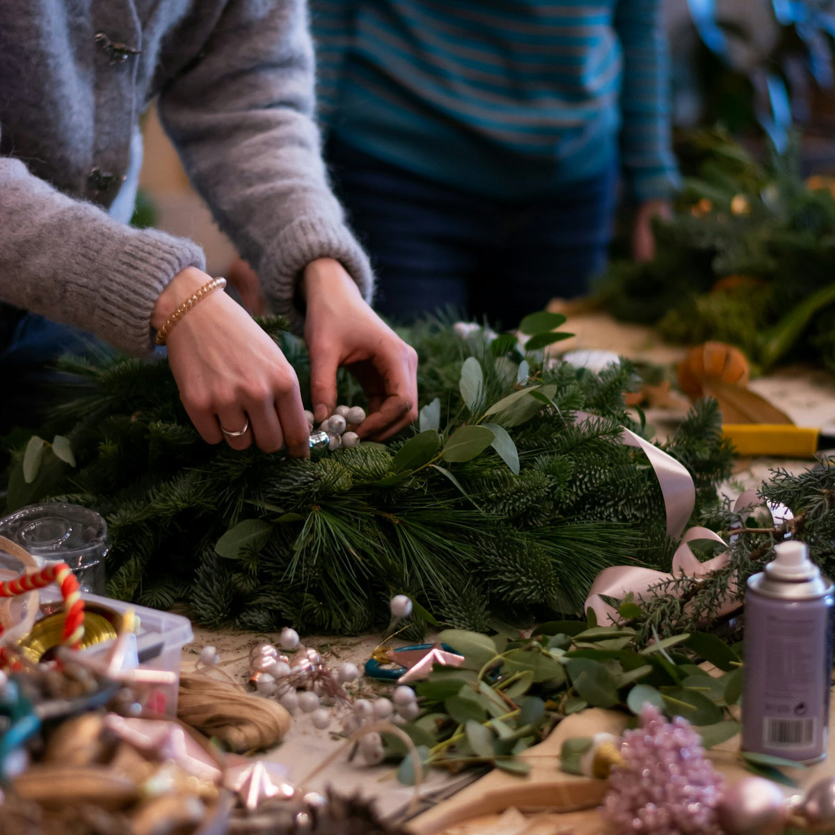 Gemeinsames Adventskranzbinden am Tisch mit Tannengrün und Deko